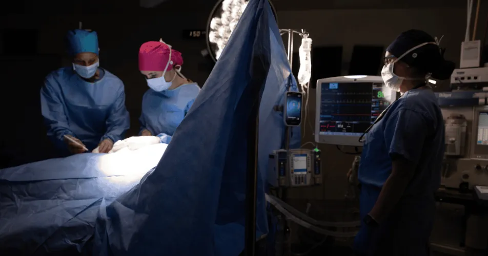 Dark OR during surgery with monitors visible